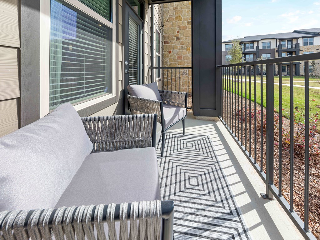 A balcony with a grey couch and a black and white patterned floor.