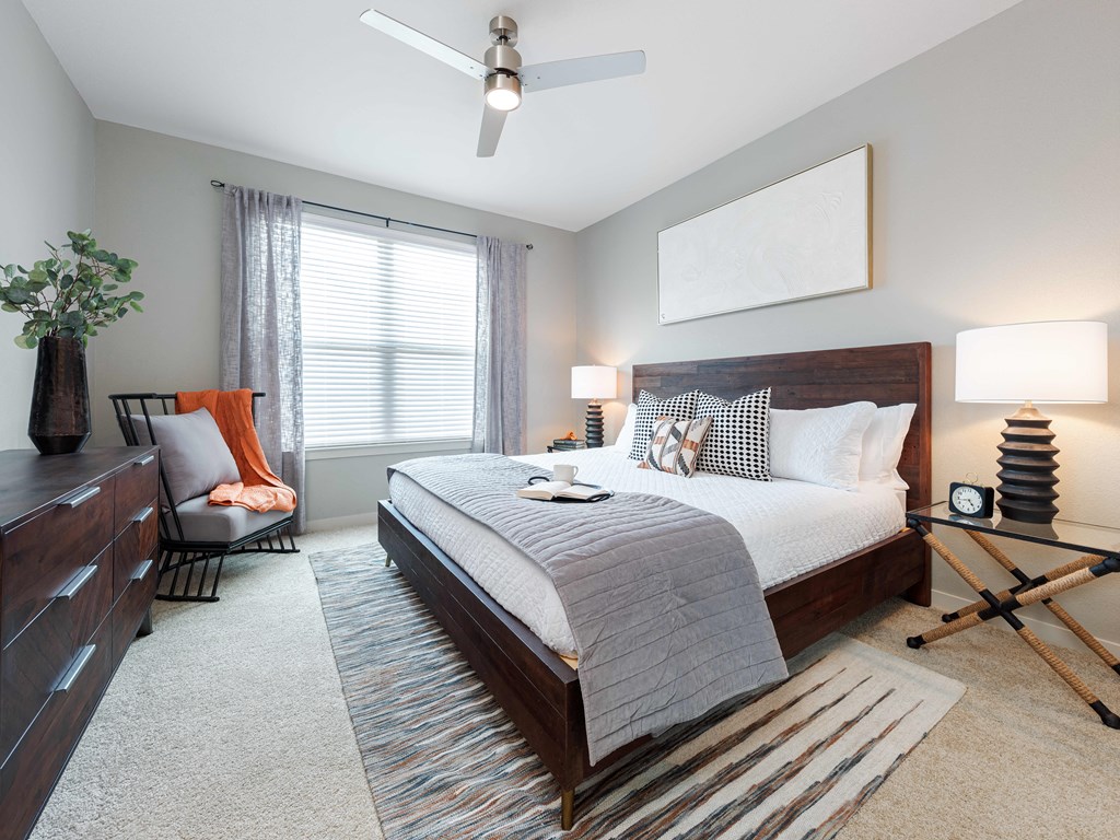 A bedroom with a large bed, a chair, and a ceiling fan.