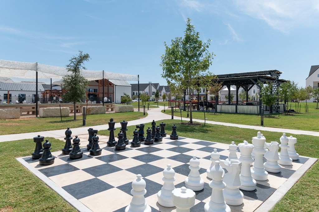 A giant chess set is set up on a grassy area.