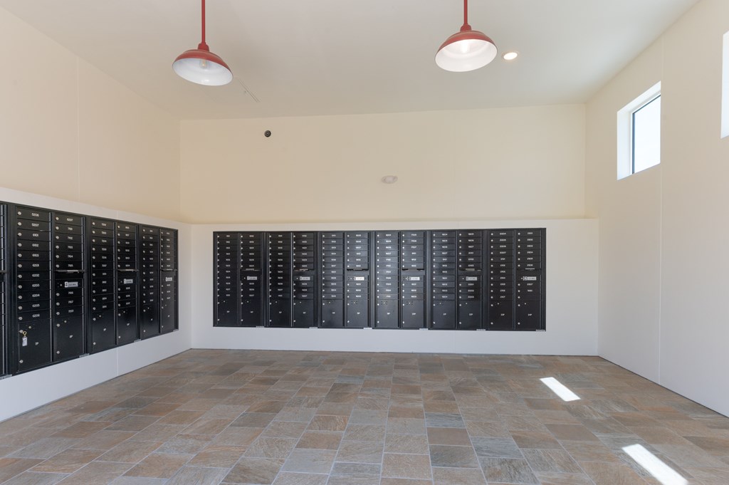 A room with black lockers on the wall and a tiled floor.