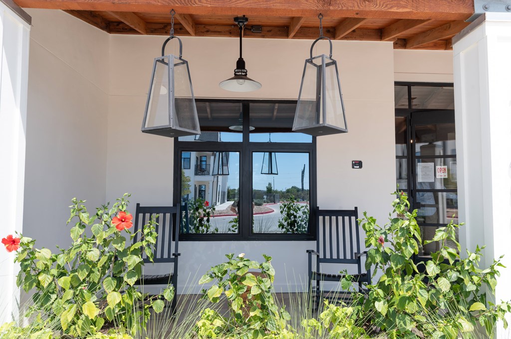 A patio with a black chair and a hanging light fixture.