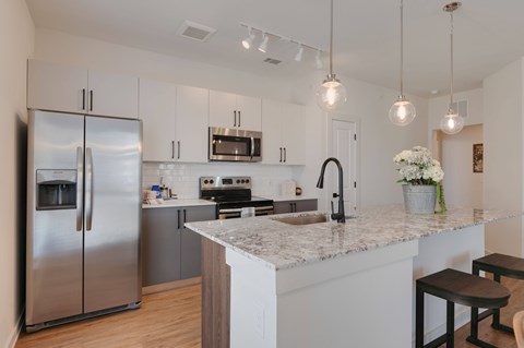A modern kitchen with a stainless steel refrigerator and a marble countertop.