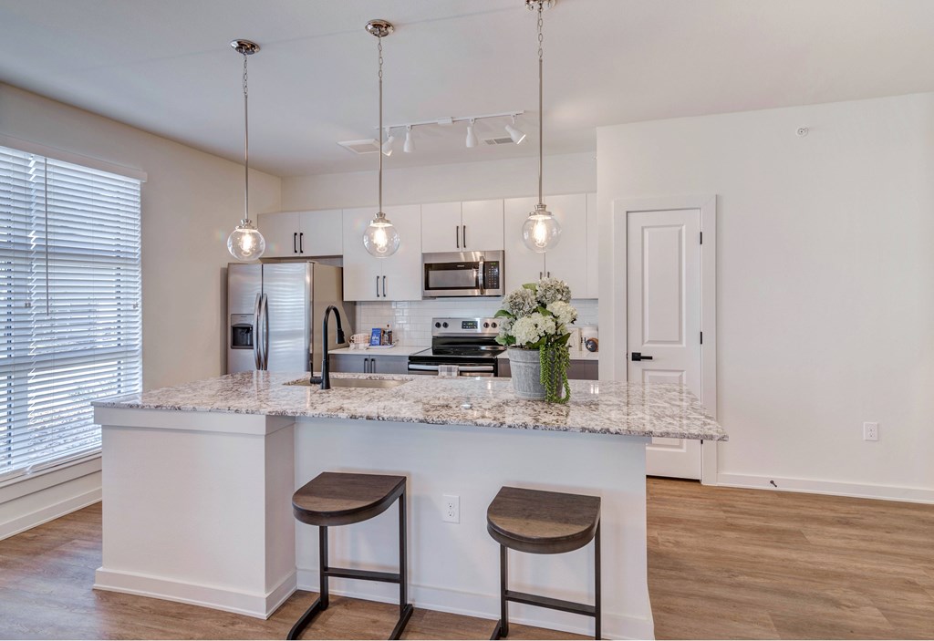 A kitchen with a marble countertop and two bar stools.