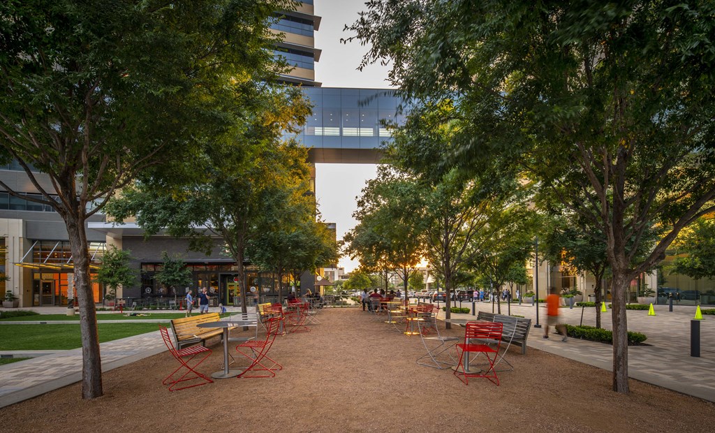 a park with red and yellow chairs and a walkway in the background