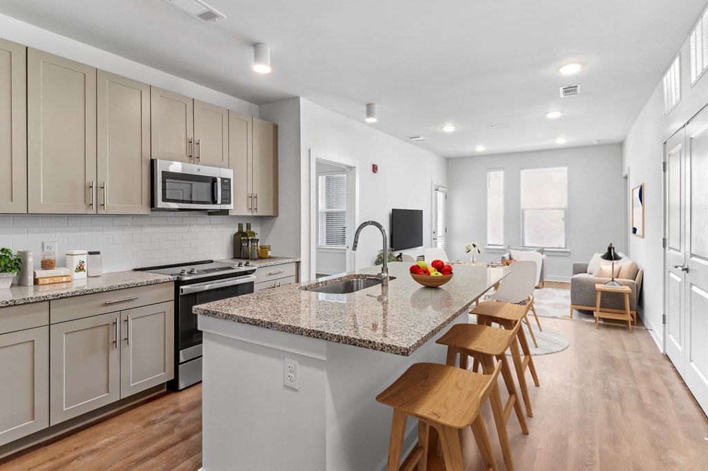 an open kitchen and living room with a marble counter top