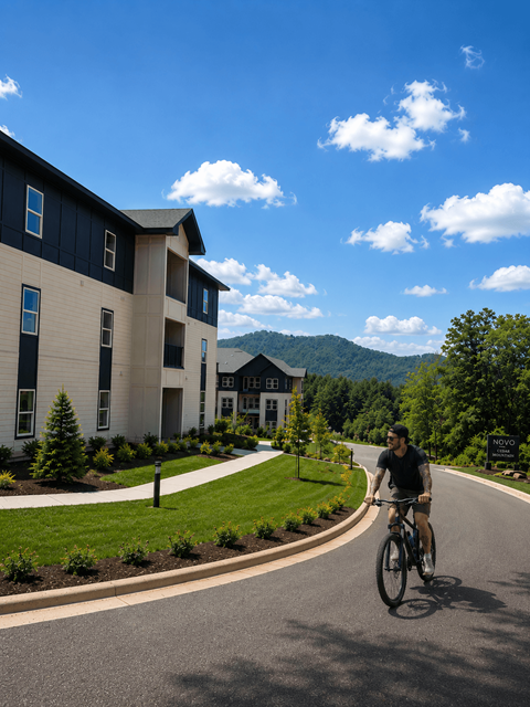 A man riding a bicycle on a road in front of a building.