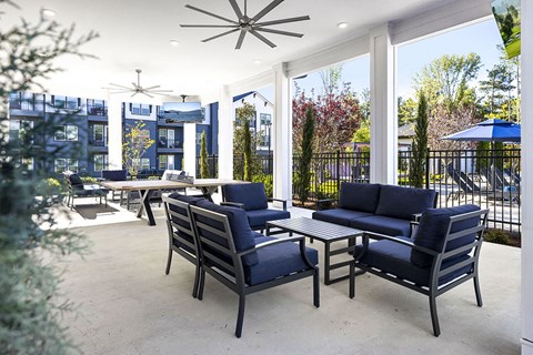 a covered patio with blue chairs and a table