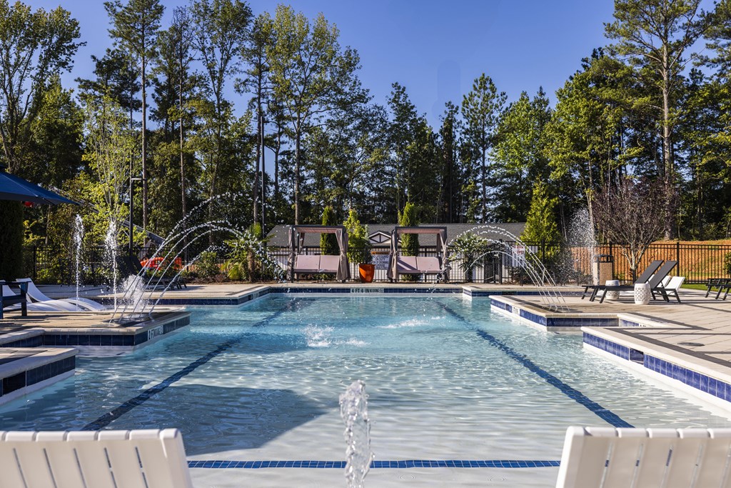 A large outdoor swimming pool with a waterfall and lounge chairs.
