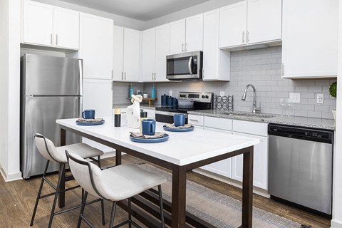 a kitchen with stainless steel appliances and a table with chairs