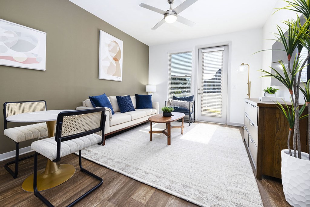 A living room with a white couch, a chair, a table, and a potted plant.
