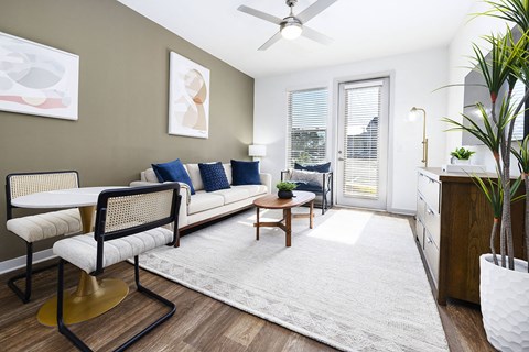 A living room with a white couch, a chair, a table, and a potted plant.