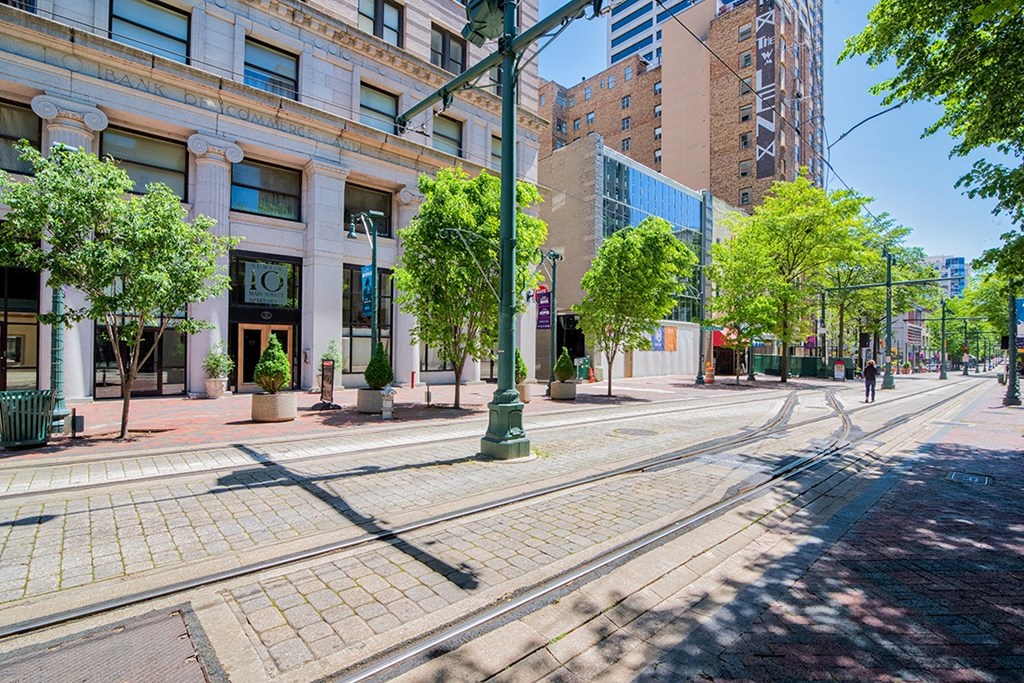 a city street with streetcar tracks and a building in the background