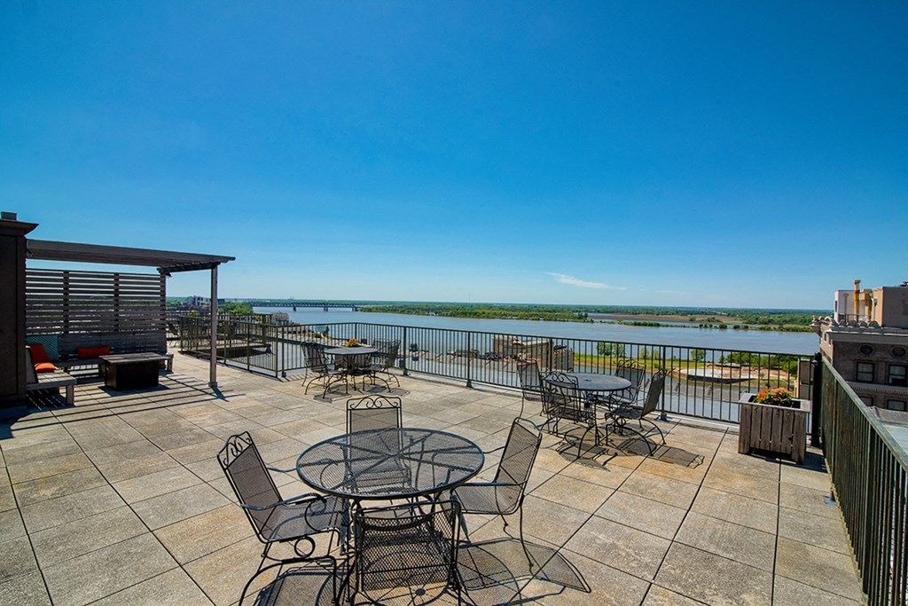 a large patio with tables and chairs overlooks a body of water