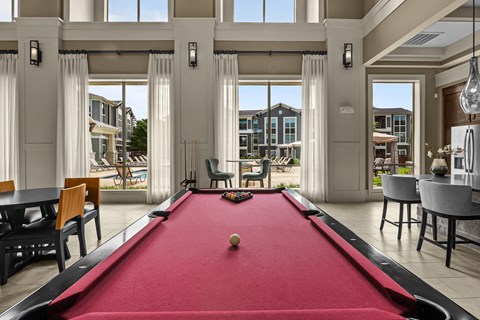 A pool table in a room with a view of the outside.
