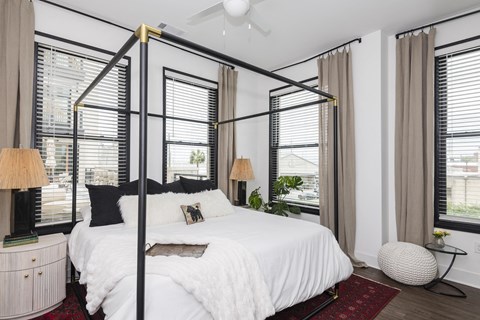 A bedroom with a four poster bed and a red rug.