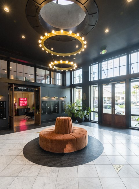 A large, circular, brown chair sits in the middle of a black circular rug.