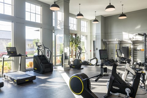 A gym with a variety of exercise equipment including treadmills, stationary bikes, and weight machines.
