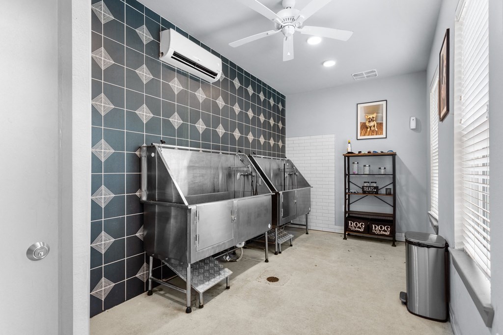 a room with a large stainless steel tub and a ceiling fan