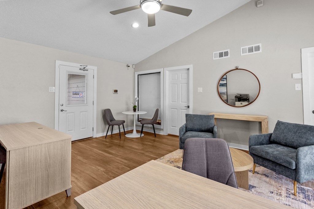 A living room with a grey couch, a wooden table, and a ceiling fan.