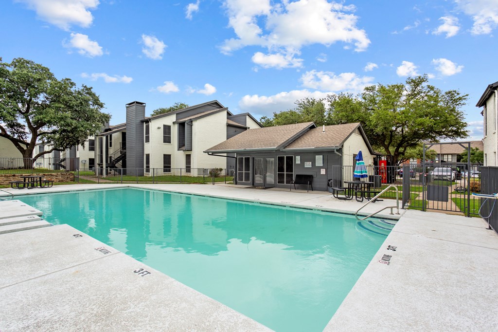 A swimming pool in a sunny day surrounded by buildings.