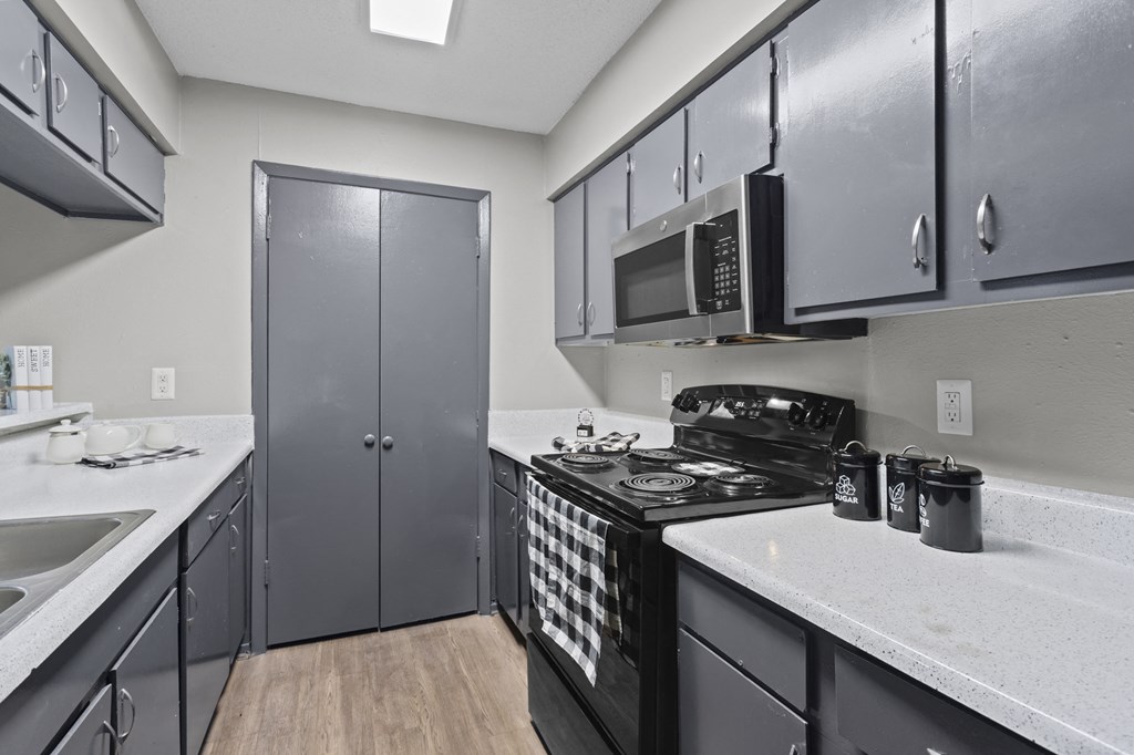 A kitchen with a black stove top oven and a black microwave above it.