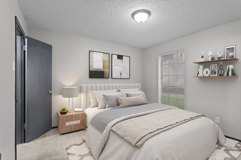 A bedroom with a large bed and a nightstand with a lamp.