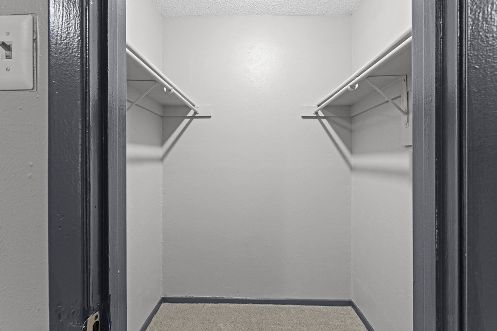 A small, empty walk-in closet with a carpeted floor and metal hangers.