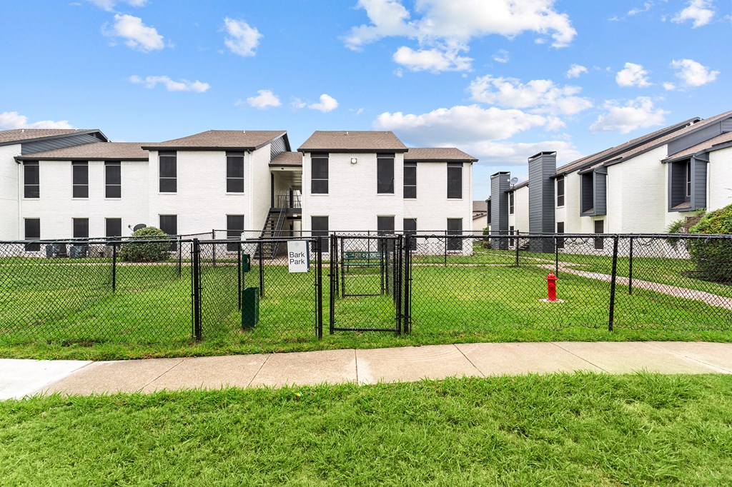 A row of white houses with black fences and a red fire hydrant.