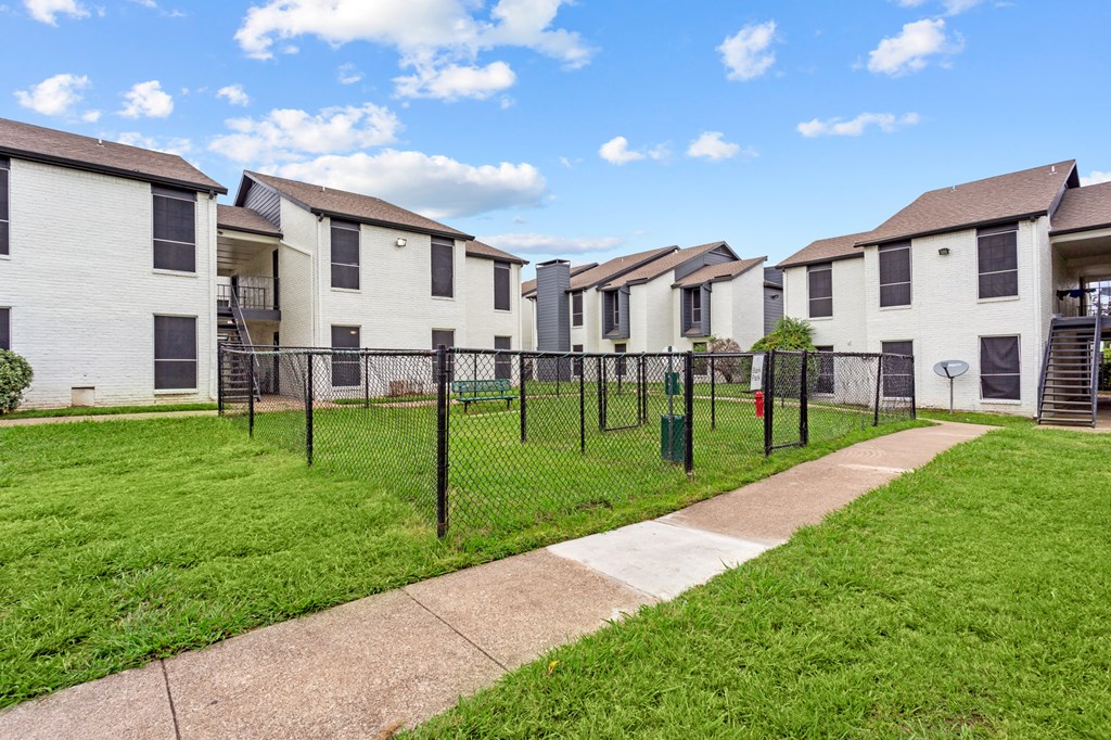 A row of white houses with green lawns and a clear blue sky.