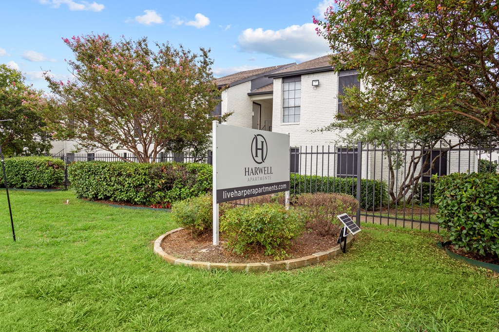 A sign for Harwell apartments stands in a grassy area.
