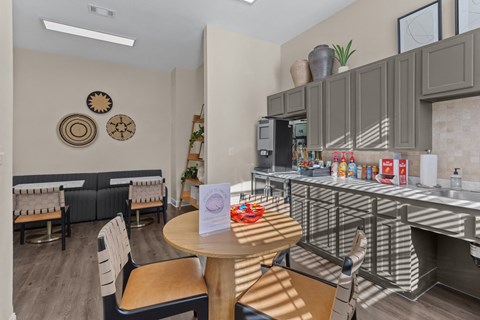 A kitchen area with a table and chairs and a counter with food on it.