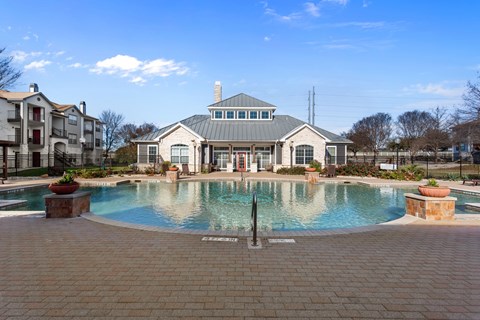 A large swimming pool in front of a building with a fountain in the middle.