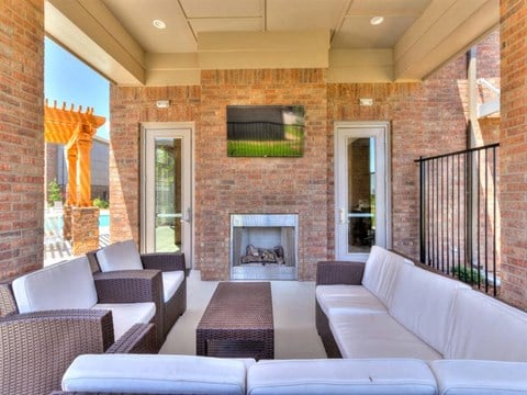 the outdoor living room has a brick fireplace and couches