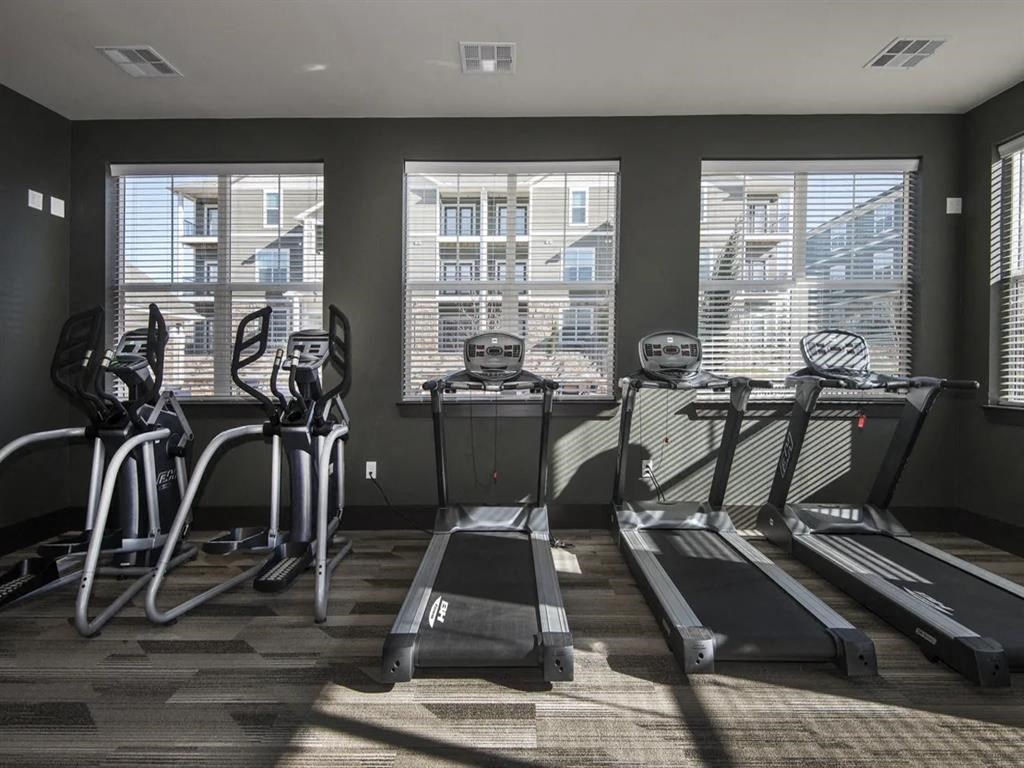 a gym with cardio equipment and windows in a building