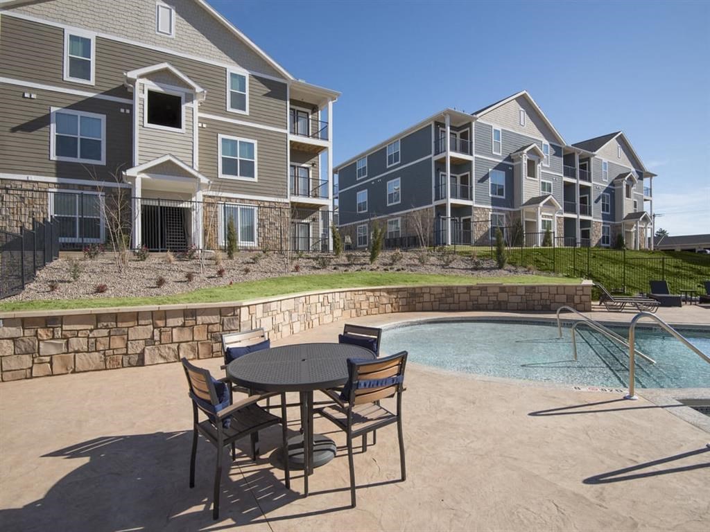 a patio with a table and chairs next to a pool