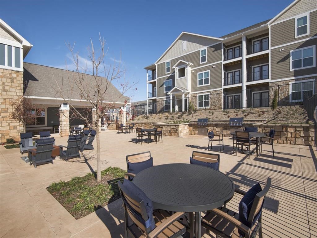 a patio with a table and chairs in front of an apartment building