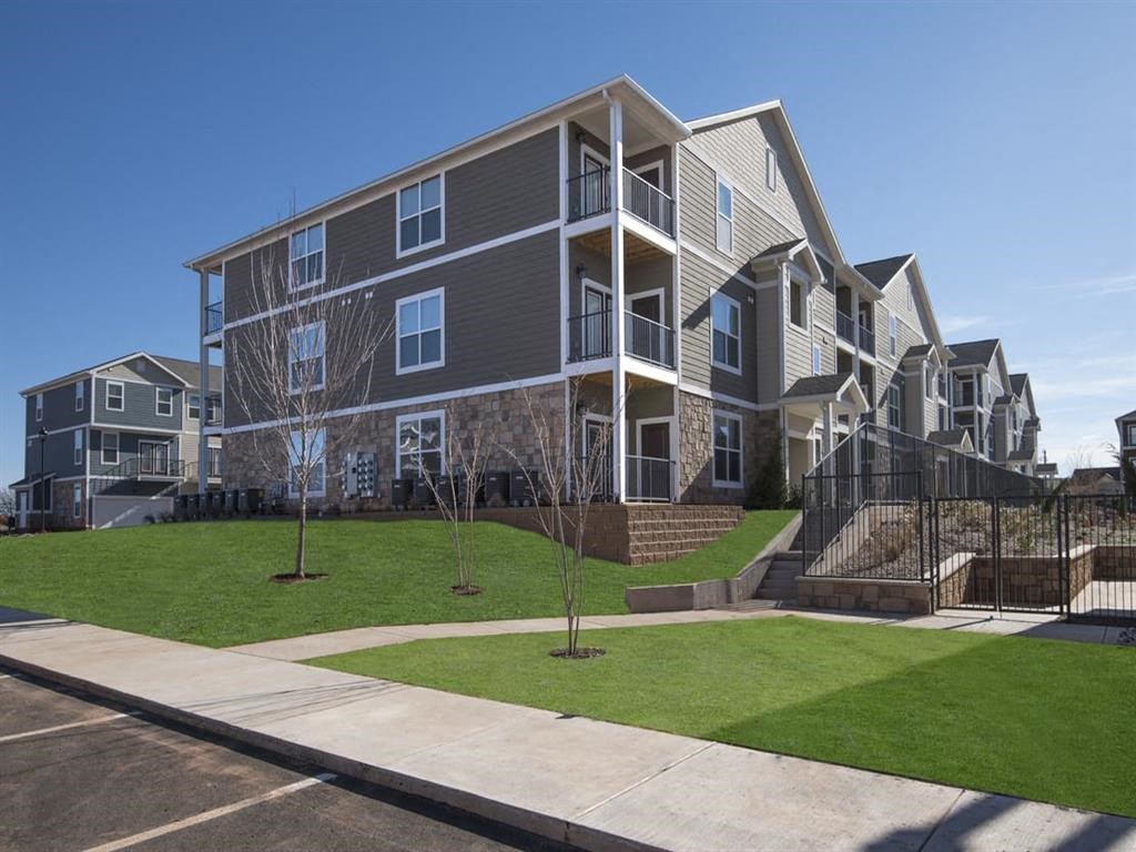 an exterior view of an apartment building with green grass and trees