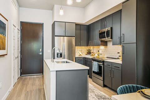 A modern kitchen with dark grey cabinets and a white countertop.