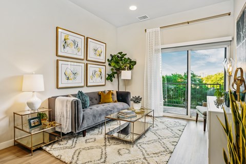 A living room with a grey couch, a coffee table, and a large window.