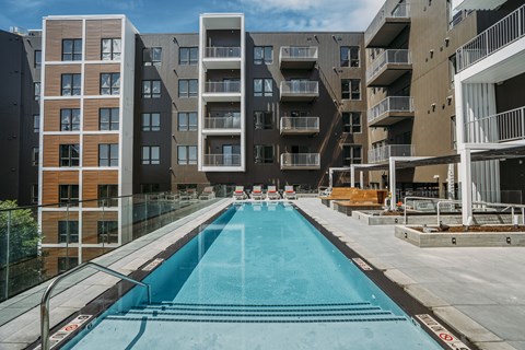 A long rectangular pool in front of apartment buildings.