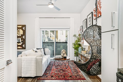 A living room with a white couch and a red rug.