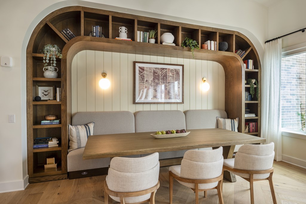 A living room with a grey couch, a wooden table, and a large arched bookshelf.