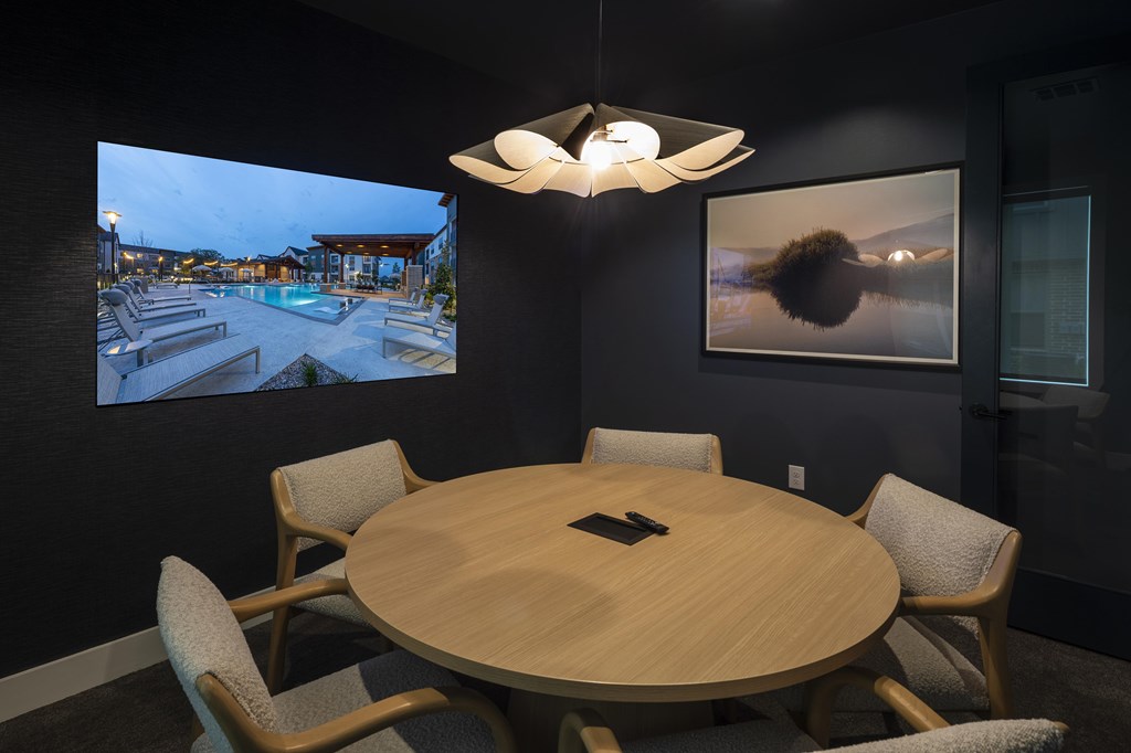 A conference room with a table, chairs, and a television screen showing a poolside view.