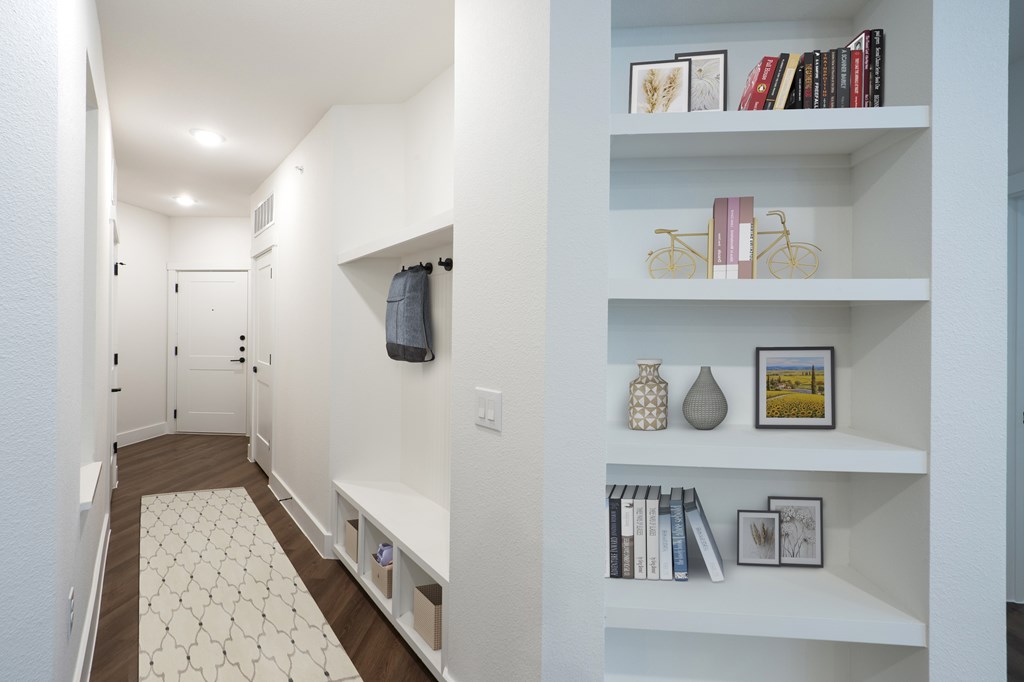 A hallway with a white shelf on the wall.
