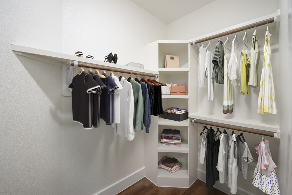 A white closet with clothes hanging and shelves.
