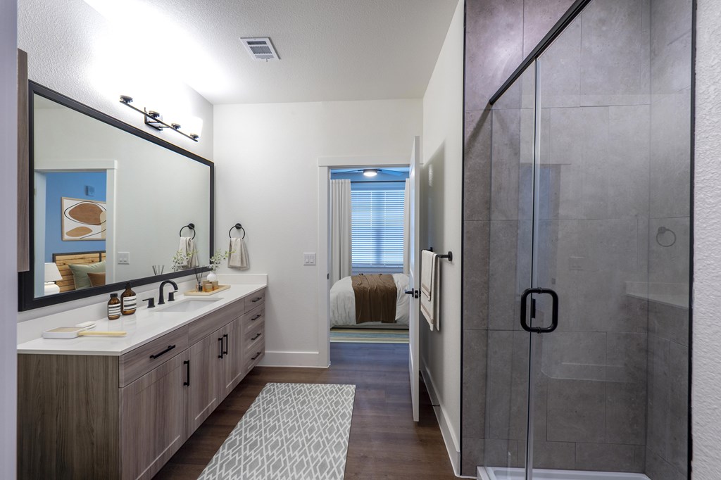 A bathroom with a sink, mirror, and shower.