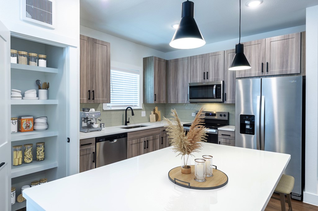 A modern kitchen with a white countertop and stainless steel appliances.