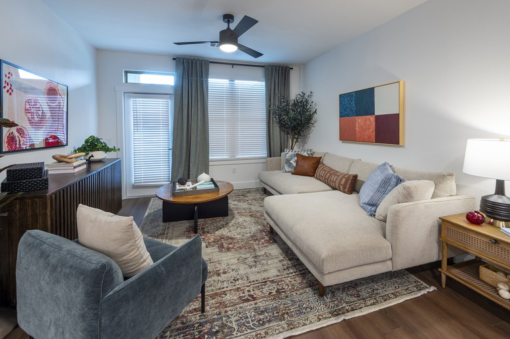 A living room with a grey couch, a blue armchair, a wooden coffee table, and a rug.