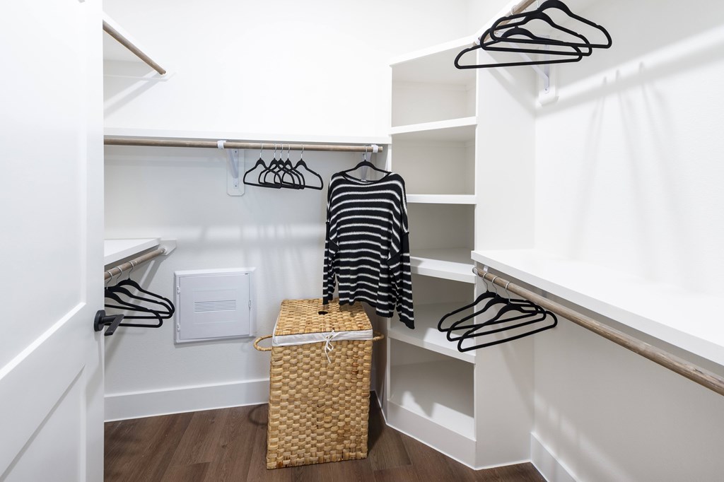 A white closet with a basket and hangers.