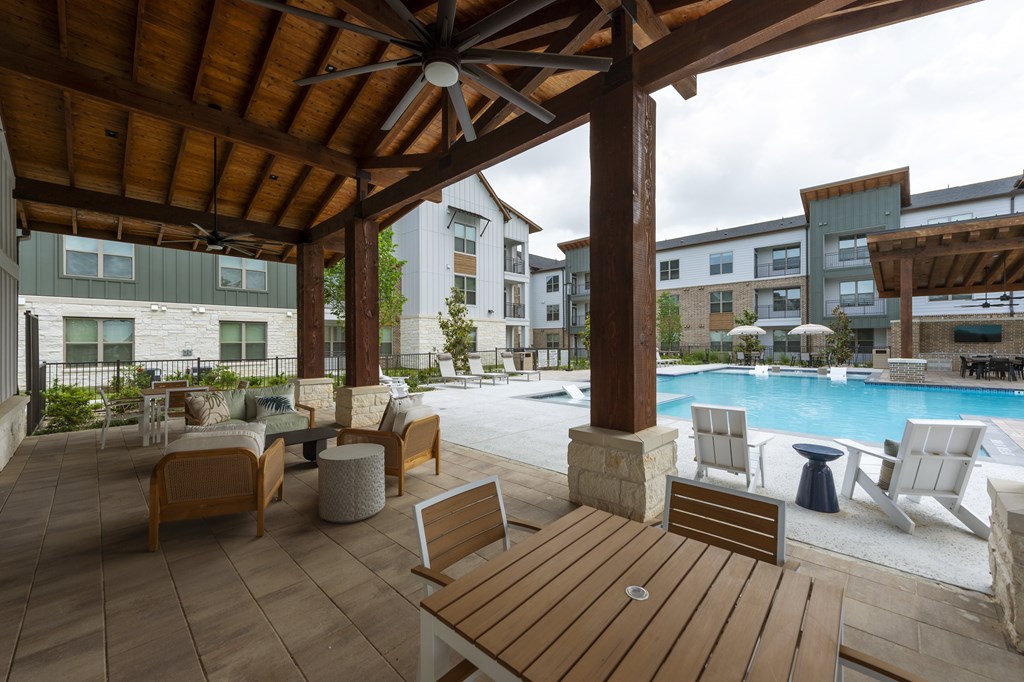 A wooden patio with a table and chairs overlooking a pool.
